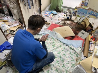 孤独死現場で手を合わせている男性スタッフ