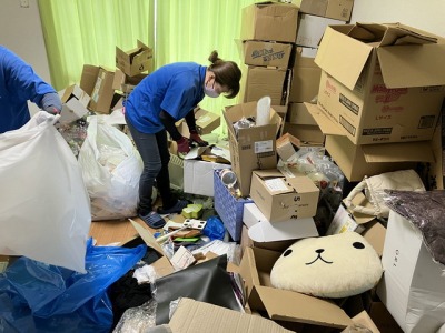 大量に荷物がある部屋を片付けているスタッフ