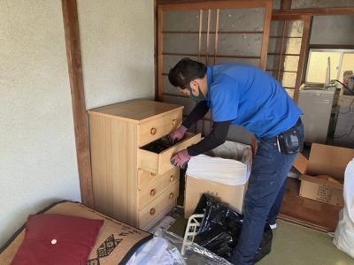 遺品整理時に家具の中を分別整理している男性スタッフ
