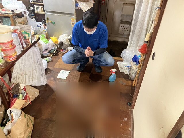 人が亡くなったと思われる場所の前で手を合わせるスタッフ