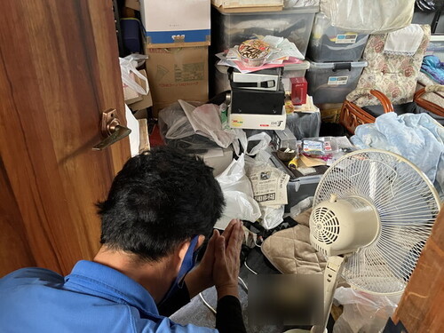 孤独死のあった現場の前で手を合わせるスタッフ