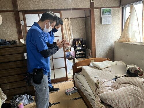 孤独死の現場で手を合わせるスタッフ