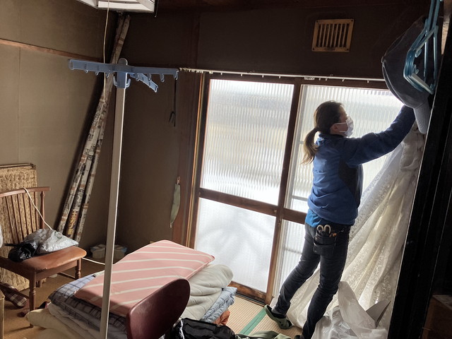 部屋のカーテンを外す女性