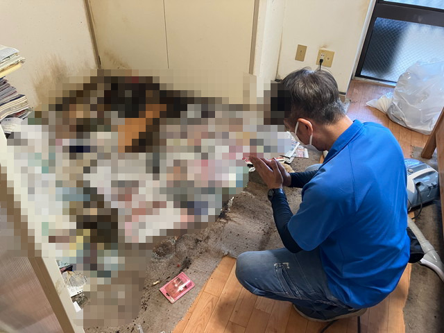 孤独死現場にて手を合わせる男性